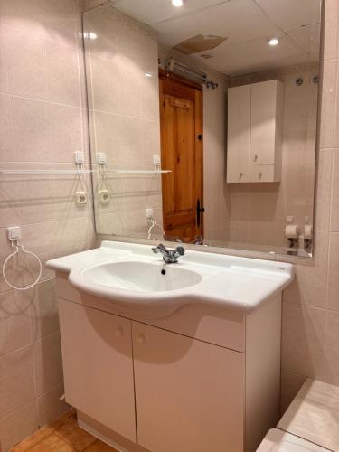 a bathroom with a white sink and a mirror at Ambiente de montaña- Chimenea, vistas y jardín- Isard 4 in Pla de l'Ermita