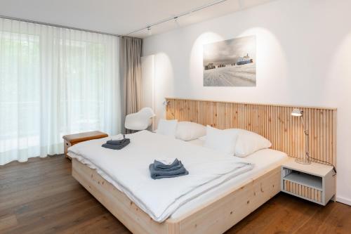 a bedroom with a large white bed and a chair at Wohnung 14 Am Januspark in Juist