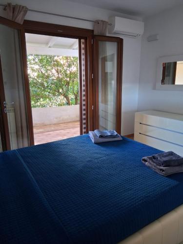 a bedroom with a blue bed with a large window at Casamare Roby in Tanaunella