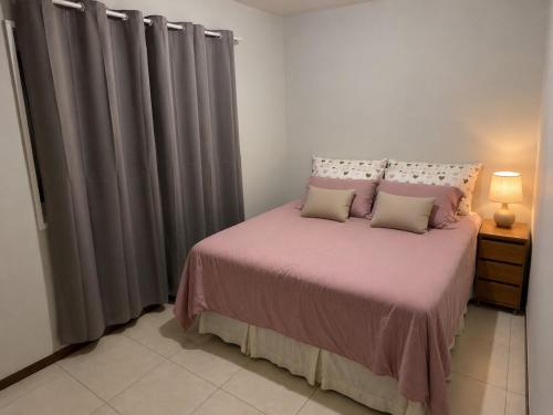 a bedroom with a bed with pink sheets and pillows at Apartamento Completo Próximo a BR in Biguaçu