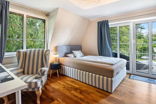 a bedroom with a bed and a chair and windows at Exklusive Traumvilla mit Sauna in Hamburg