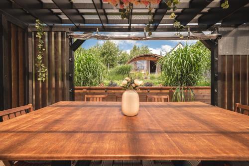 a wooden table with a vase sitting on a patio at Osada Marchowo in Kielno