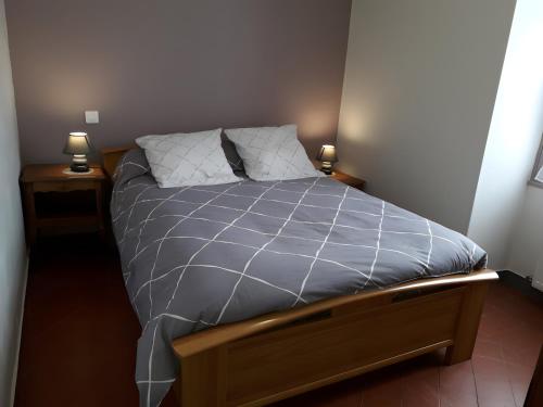a bed in a room with two lamps on tables at Gîte la Roche du Gravillot in Château-Chinon