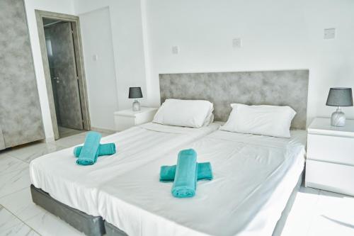 a large white bed with two blue slippers on it at Nissi Avenue Suites in Ayia Napa