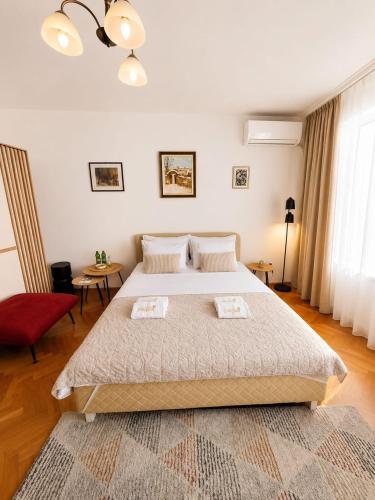 a bedroom with a large bed and a red chair at Apartments Dragulji Kruševac Central Stay in Kruševac