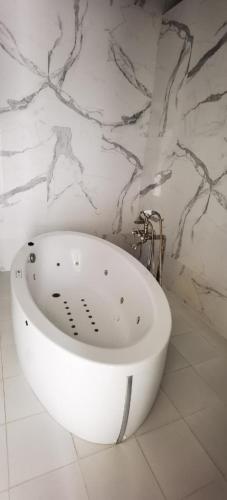 eine weiße Badewanne in einem Badezimmer mit Marmorwand in der Unterkunft hôtel Benkachour in Oujda
