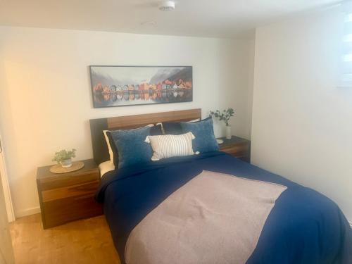 a bedroom with a blue bed with a painting on the wall at La Pergola-1 in Quebec City