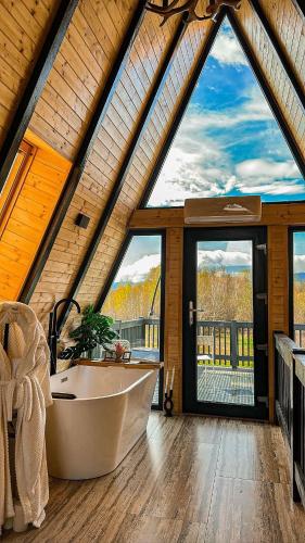 a bathroom with a tub in a room with large windows at Cabana Ross-A in Poenari