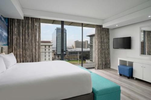 a bedroom with a large bed and a large window at Protea Hotel by Marriott Cape Town North Wharf in Cape Town