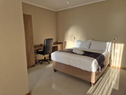 a bedroom with a bed and a desk and a chair at The Grand Village in Mahikeng