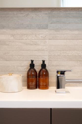 two bottles of soap sitting on a bathroom counter at 3 Bed Stylish Beachfront Retreat in Roche
