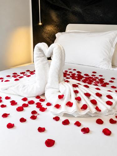 a bed with red rose petals on it at Athos Hotel in Riva del Garda