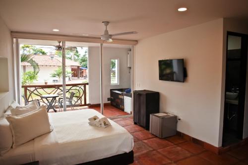 a bedroom with a bed and a tv and a balcony at Hotel Boutique Villas de San Sebastián in Villavicencio