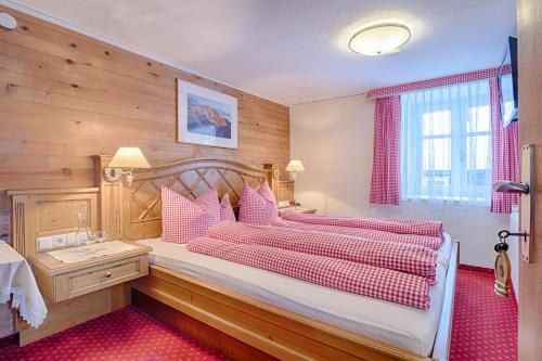a bedroom with a large bed with pink pillows at Walch's Camping & Landhaus in Braz
