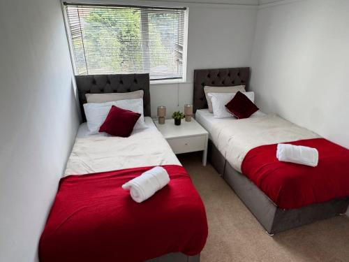 two beds in a room with red and white sheets at Spacious 3 Bed House in Northampton - Sleeps 6 - Driveway Parking - Fast WiFi in Kingsthorpe