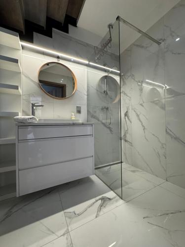 a bathroom with a shower and a sink and a mirror at Apartamenty Prusa in Mikołajki