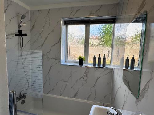 a bathroom with a shower and a sink and a window at Spacious 3 Bed House in Northampton - Sleeps 6 - Driveway Parking - Fast WiFi in Kingsthorpe