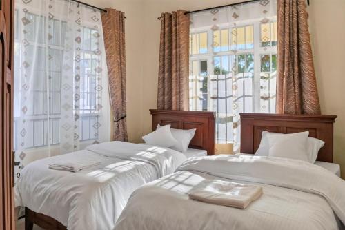 two beds in a room with two windows at Hakika Homes in Olmotoni