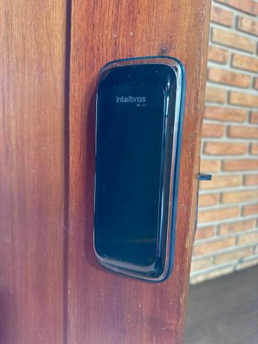 a cell phone sticking out of a wooden door at Suíte com Ar condicionado no Centro de Botucatu in Botucatu