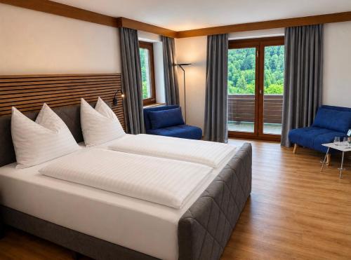 a bedroom with a large white bed and blue chairs at Hotel Haus Sonnblick in Bad Kleinkirchheim