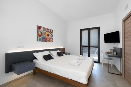 a bedroom with a bed and a desk and a television at ByAma Holiday House in Menfi