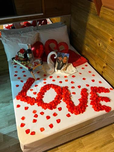 a bed with red flowers and a sign that says love at Chalés Refúgio nas montanhas in Guaratuba