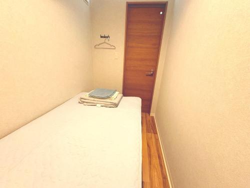a small room with a bed and a wooden door at Hitori Otaru in Otaru