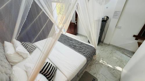 a bedroom with a canopy bed with pillows at Mount Breeze Ella in Ella