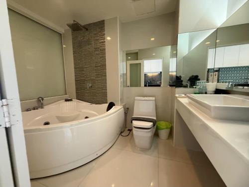 a bathroom with a tub and a toilet and a sink at View Talay 6 Pattaya Beach Apartment by Honey in Pattaya