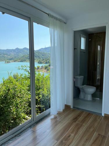 a bathroom with a toilet and a large window at Lake Breeze in Gjokaj