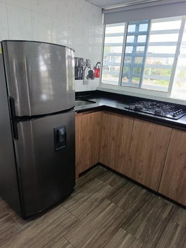 a stainless steel refrigerator in a kitchen with wooden cabinets at Casa de alejo in Pereira