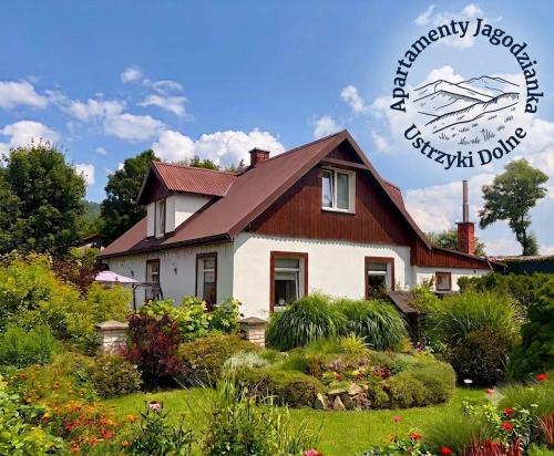 a house with a garden in front of it at Apartamenty Jagodzianka - Jacuzzi, Sauna, Hot-bania, Tężnia in Ustrzyki Dolne