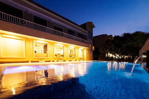 a swimming pool in front of a building at night at DL Hotels & Resorts Corbett in Dhikuli