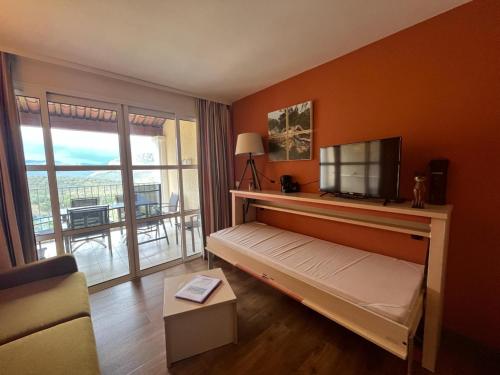 a room with a bed with a television and a balcony at Cap Estérel by Actisource in Agay - Saint Raphael