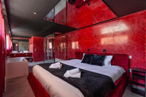 a red bedroom with a large bed and a bath tub at L'Interdit, Confort et Sensualité in La Ferté-Gaucher
