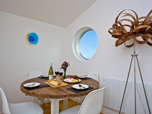 a dining room with a wooden table and white chairs at Una Aurum 56 in St Ives