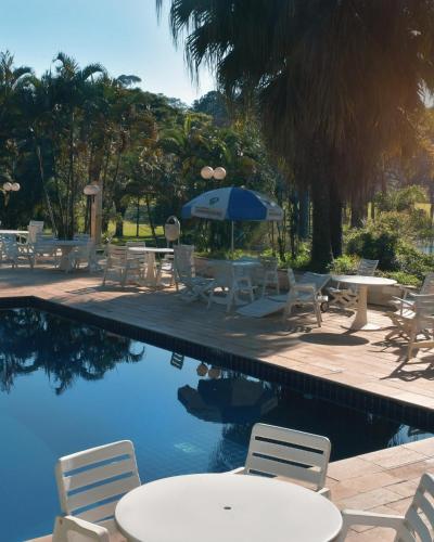 a pool with chairs and tables and an umbrella at Hotel Amoreiras in Extrema