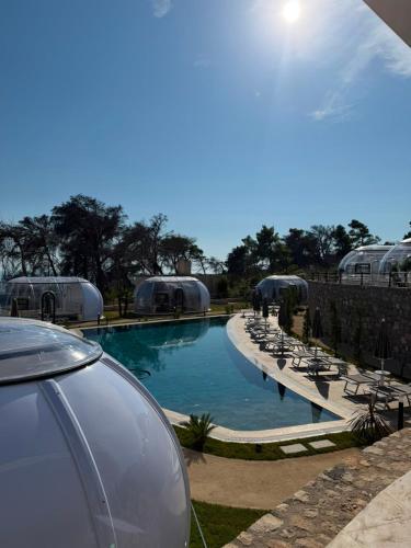 a swimming pool with chairs and a car parked next to it at Piccolo Paradiso - Glamping Resort in Shëngjin