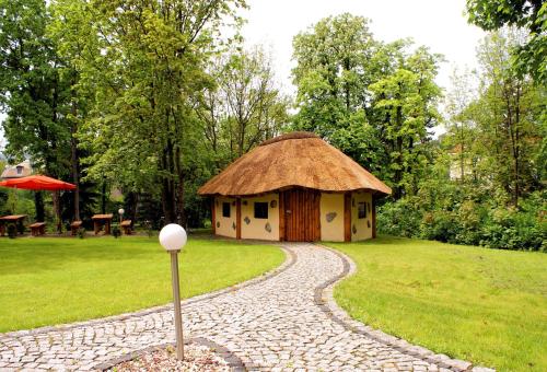 a small hut with a thatched roof in a garden at Villa Carmen in Kudowa-Zdrój