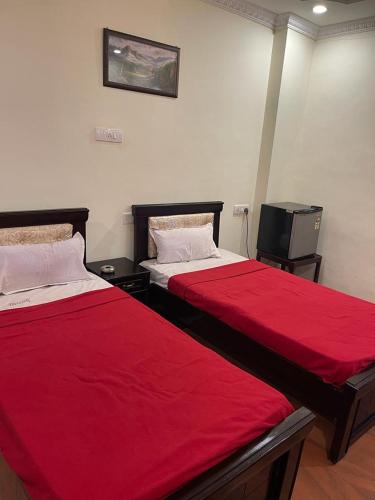 two beds in a room with red sheets and a tv at Milan Hotel in Zahirābād