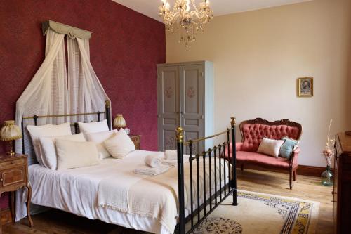 a bedroom with a bed and a chair and a chandelier at Chateau Gioux in Saint-Pierre-Bellevue