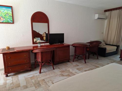 a hotel room with a desk with a television and a mirror at Just in paradise in Baie Nettle
