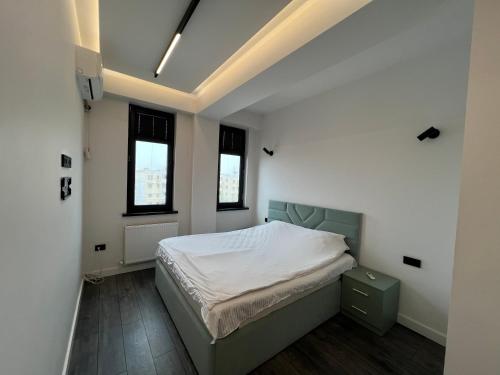 a bedroom with a bed and two windows at Hi-Tech Apartment in Tashkent