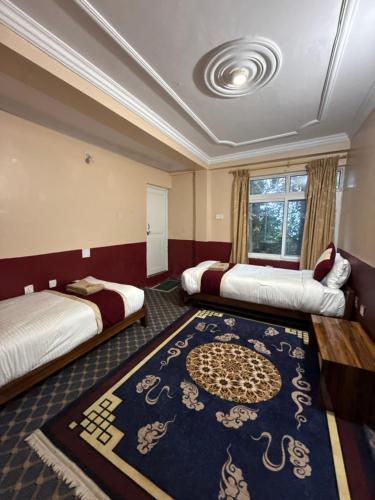 a hotel room with two beds and a rug at Pahuna Ghar Homestay in Tānsen
