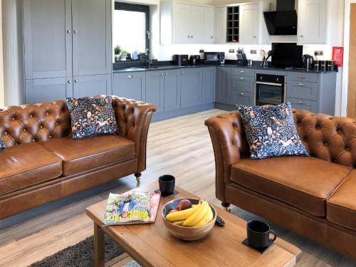 a living room with two brown leather couches and a table at The Old Dairy - Uk31253 in Middleton