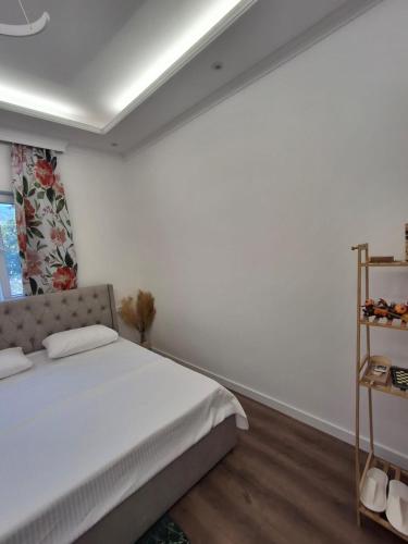 a white bedroom with a bed and a shelf at Hotel Bar Restorant RRAHIMI in Shënmëri