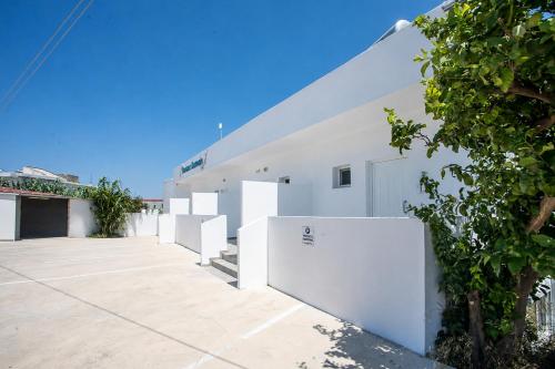 a white building with white walls and a tree at Dorians - Faliraki in Faliraki
