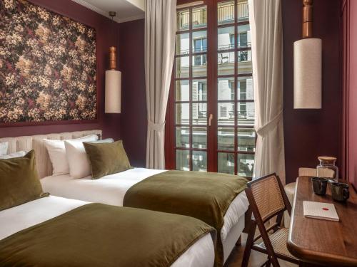 two beds in a room with a desk and a window at Lazare Nomade in Paris