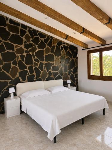 a white bed in a room with a stone wall at Casa Lluna De Mar in L'Ampolla