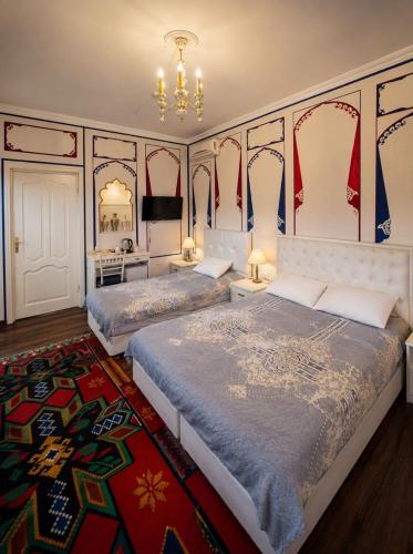 a bedroom with two beds and a rug at Hotel Chorminor 110 m to Old Town GET EARLY CHECK IN AND CHECK OUT in Bukhara